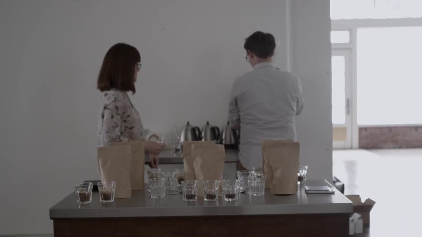 A man and woman stand in front of the table with coffee mugs in glasses