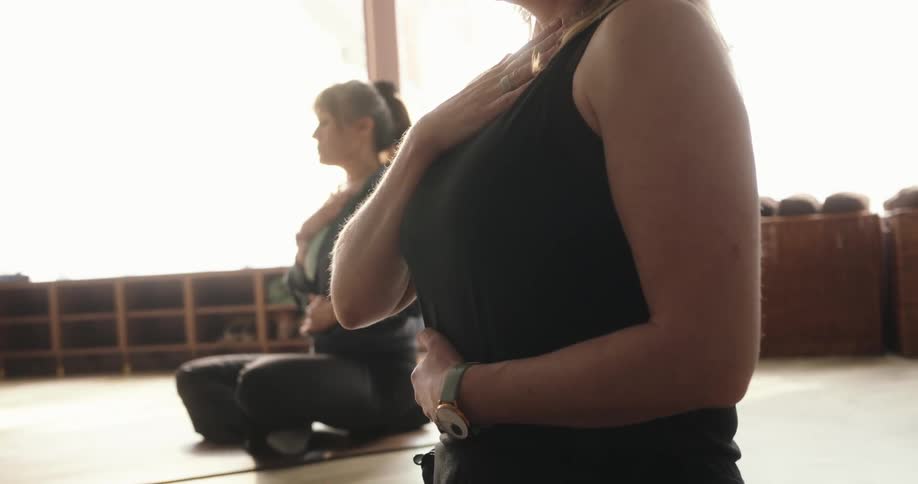 A serene woman meditates with her eyes closed, practicing deep breathing in a sun-drenched studio