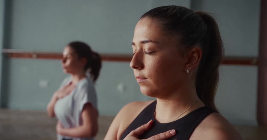 Close up of a serene woman with her eyes closed, practicing mindful breathing in a yoga studio