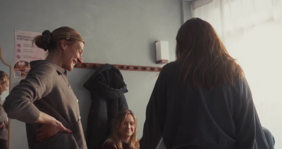 A group of cheerful women greet each other with warm hugs in the friendly atmosphere of a fitness studio's locker room