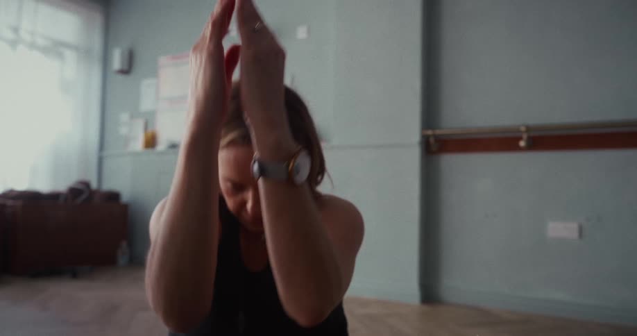A calm woman practices a yoga flow, moving gracefully through poses in a serene studio with natural light