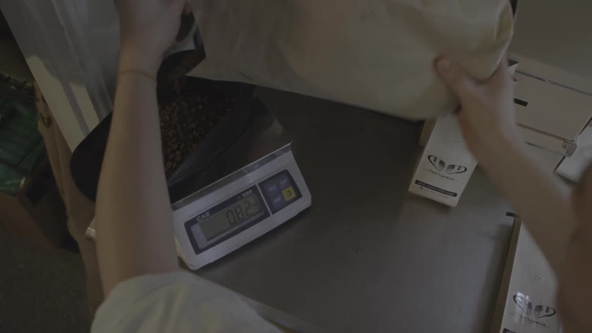 Man pouring coffee beans into container on weight scale