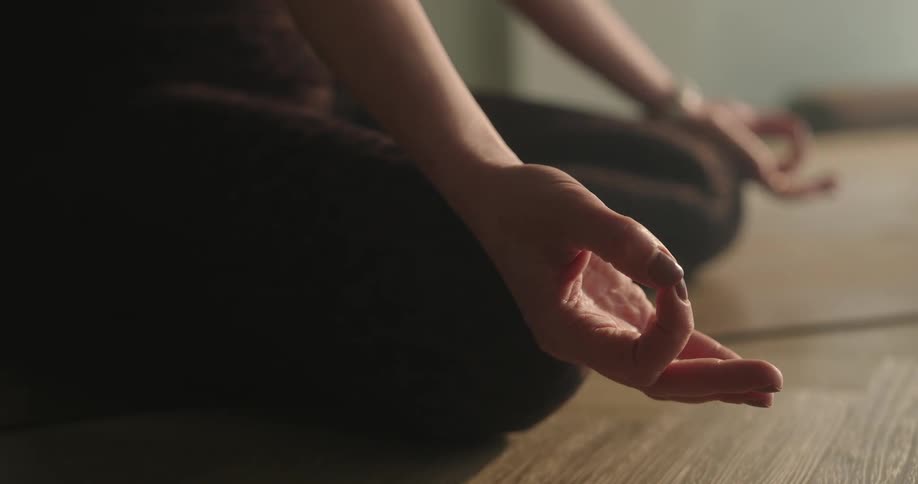 Close-up of a woman's hand in a serene mudra pose during a quiet meditation session