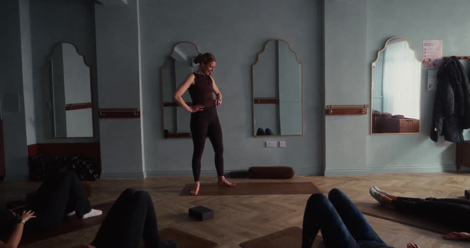 Slow-motion view of a female yoga instructor teaching her class in a modern, calm studio