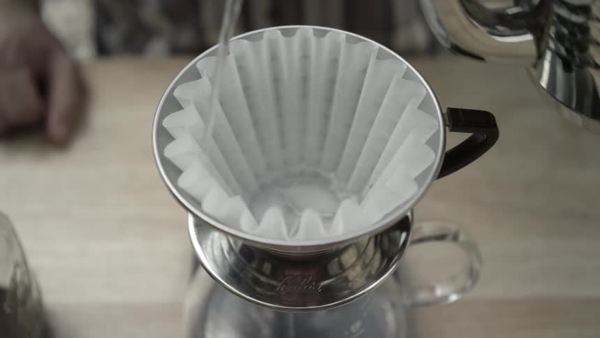 A person pours hot water into a coffee filter