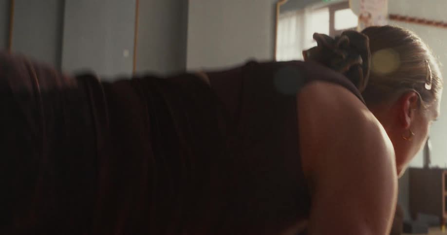 Slow motion close-up of a woman flowing through yoga poses, transitioning from Chaturanga to Upward and Downward-Facing Dog