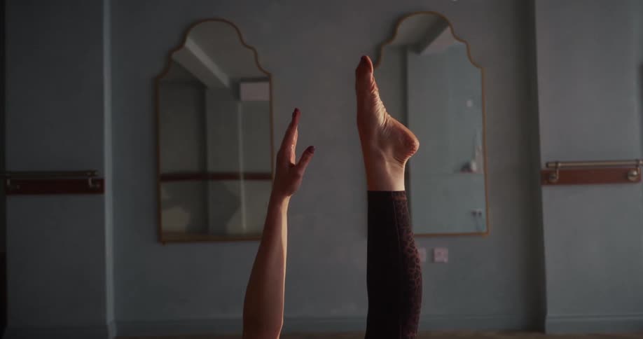 A woman's extended arm and leg point towards the ceiling as she practices yoga in a calm, minimalist studio