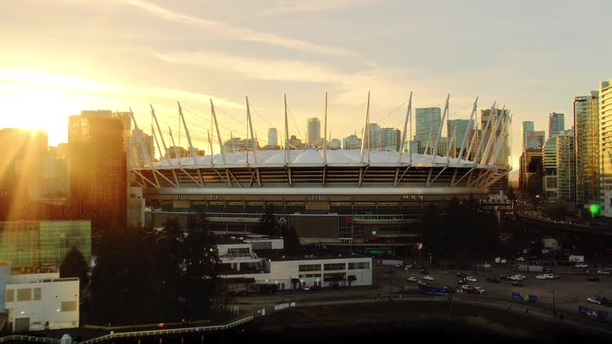 Golden sunset glows behind BC Place Stadium as the camera pulls back to reveal the Vancouver skyline and False Creek harbor