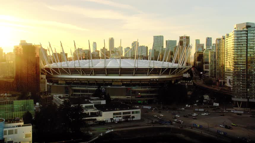 Slow aerial orbit of BC Place stadium and downtown Vancouver's modern architecture glowing in the golden light of sunset
