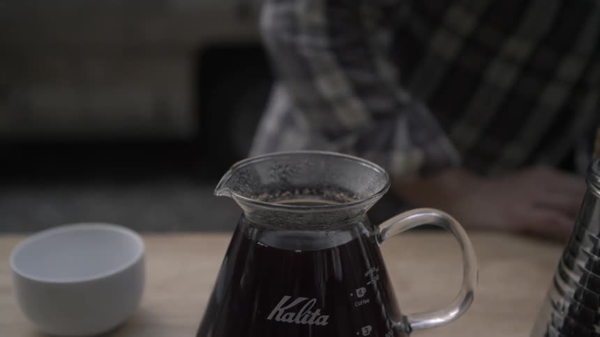 A person removes the cone filter from a coffee maker