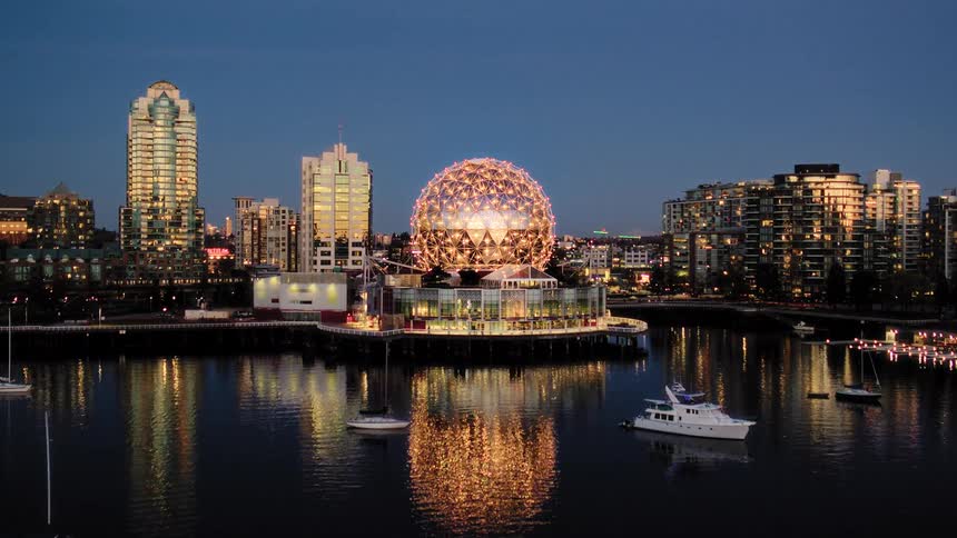 A beautiful aerial shot of Vancouver's Science World at dusk, with its golden lights reflecting on the water amidst the city skyline
