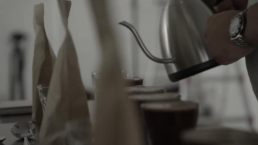 A person pours coffee into glasses along the table
