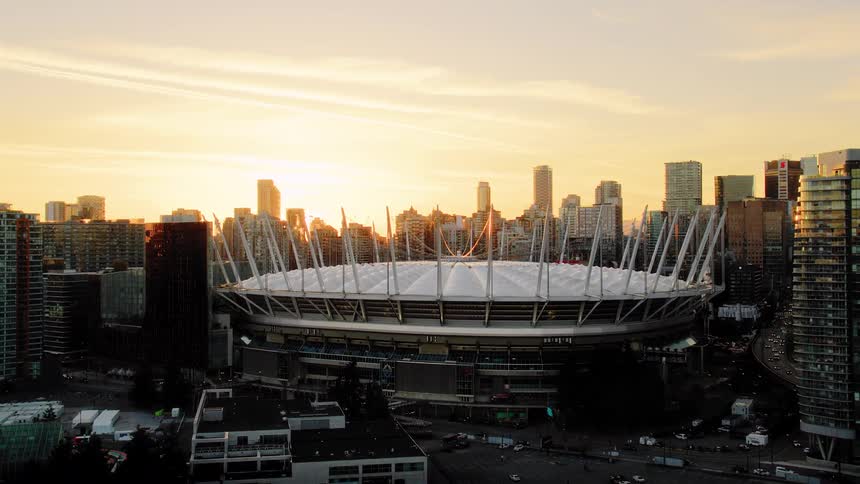 Aerial pull-back shot reveals BC Place Stadium and the Vancouver city skyline during a stunning golden hour sunset