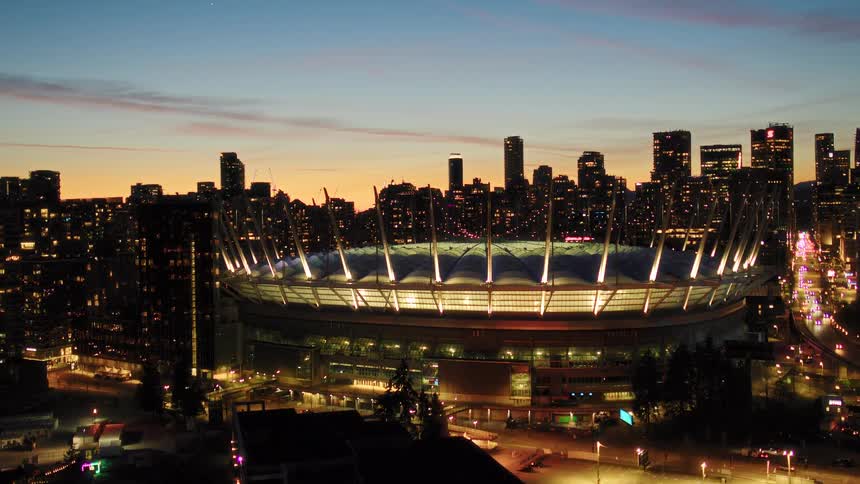Stunning aerial reveal of Vancouver's BC Place stadium and downtown skyline illuminated against the beautiful twilight sky