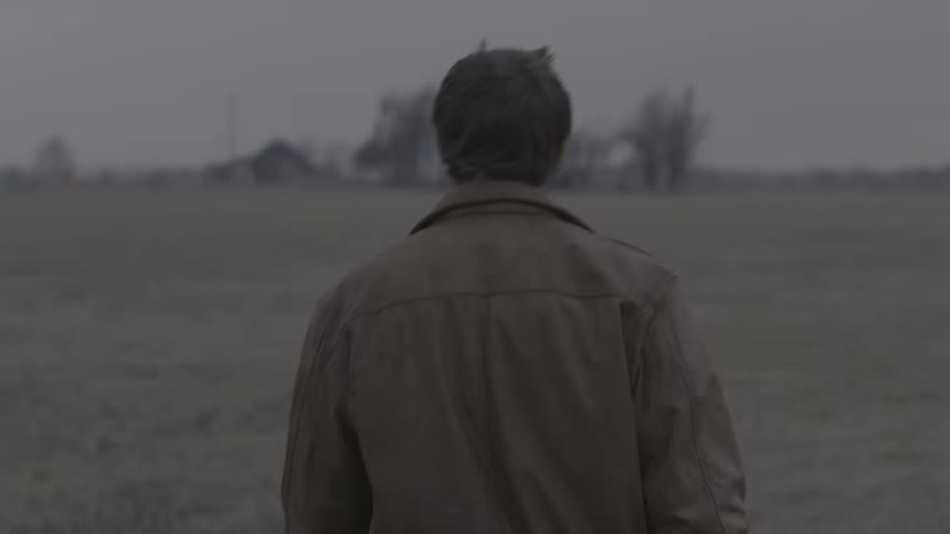 Man walking in a dry field on cloudy evening