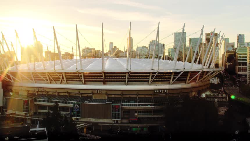 An aerial pan of the iconic BC Place stadium in Vancouver reveals the city skyline during a golden sunset