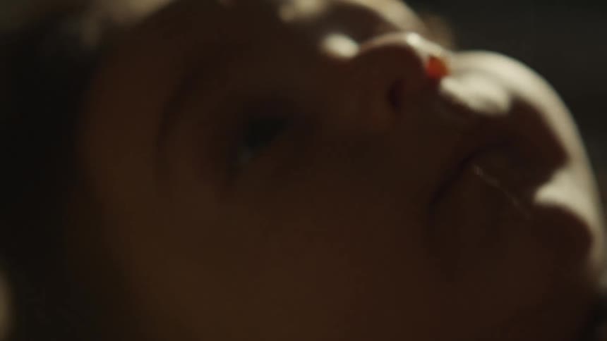 An artistic and blurry close-up of a newborn baby's eye as they rest peacefully in a dimly lit room
