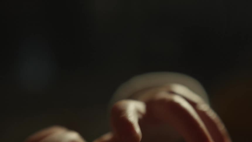 A soft, blurry close-up of a newborn baby's tiny hand moving gently in a warm, dimly lit room