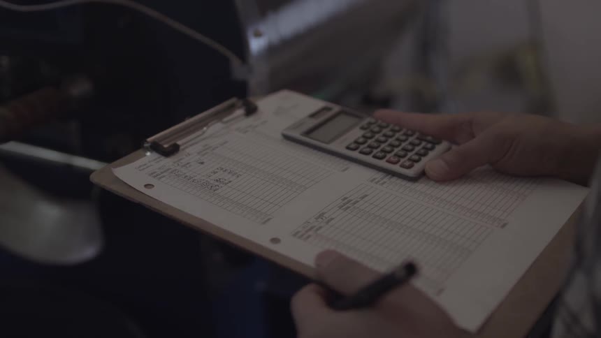 A person is using a calculator on a clipboard