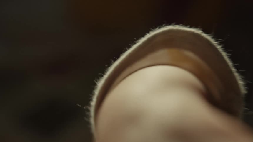 A macro close-up shot captures the delicate and slow movements of an elderly person's hand in soft, warm light