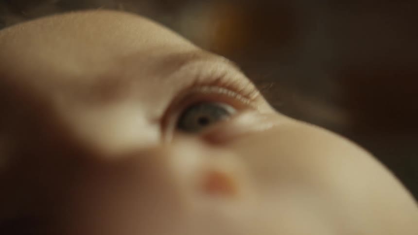 An intimate and dreamy extreme close-up shot of a newborn baby's face as their curious eyes look around