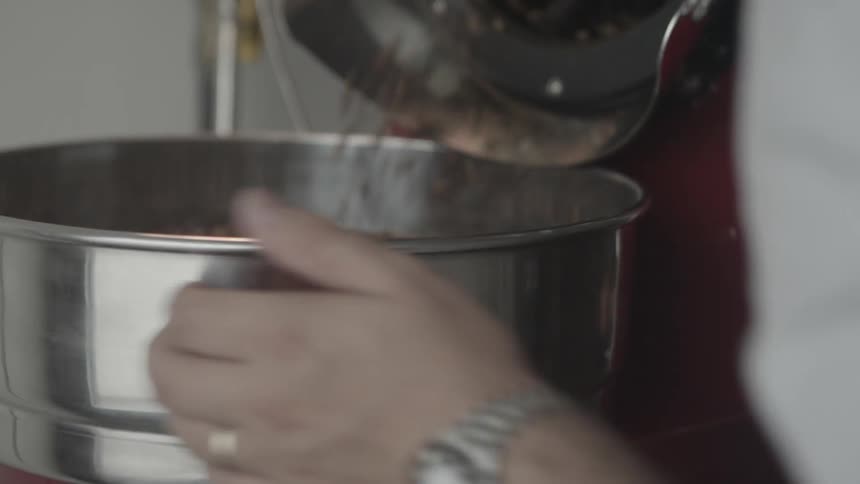 Person spins bowl while coffee beans pour out from machine into bowl