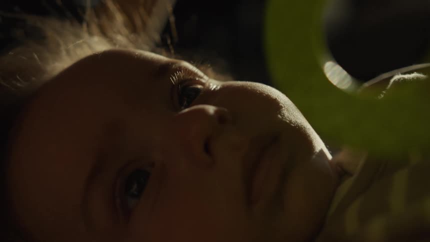 An intimate close-up of a newborn baby's face as they calmly lie awake in soft, warm lighting