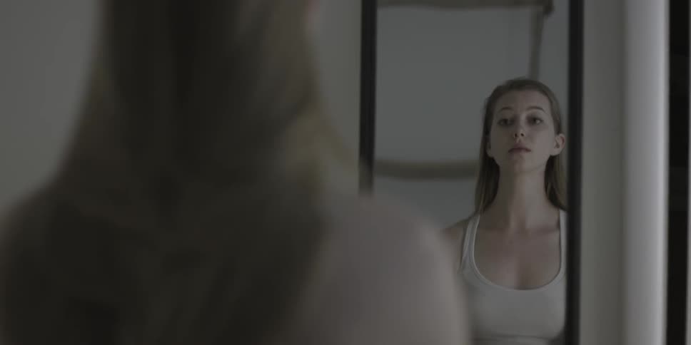 A woman stands in front of a mirror