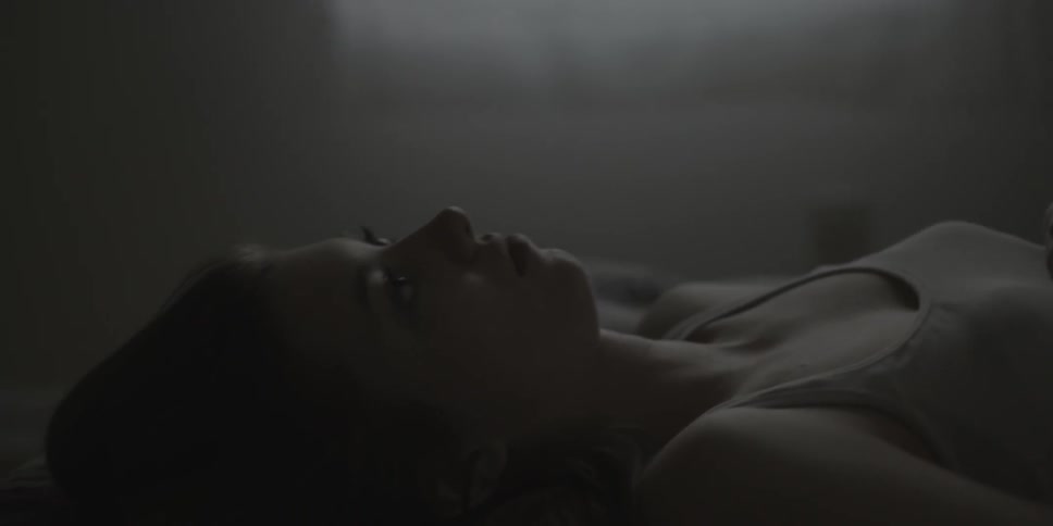A woman is laying in bed snapping her fingers
