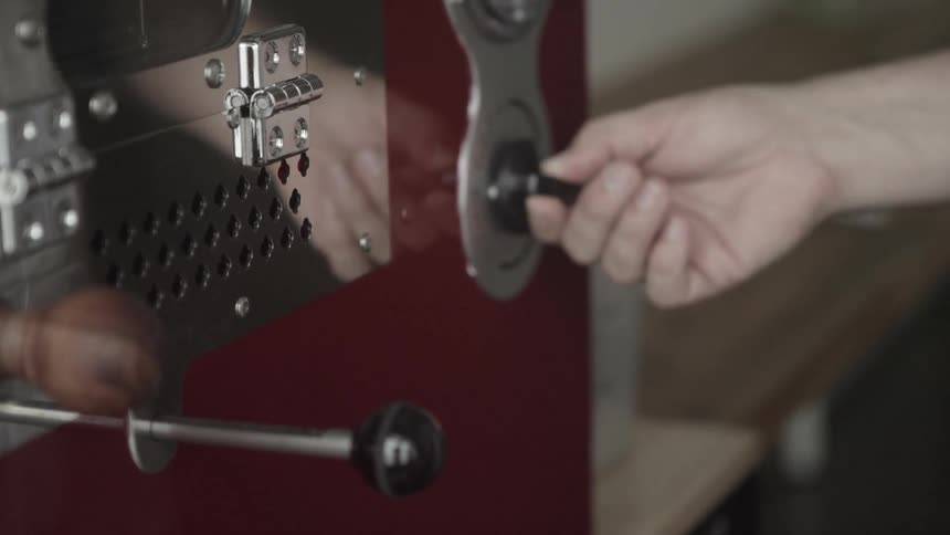 A hand turns a knob on a piece of machinery