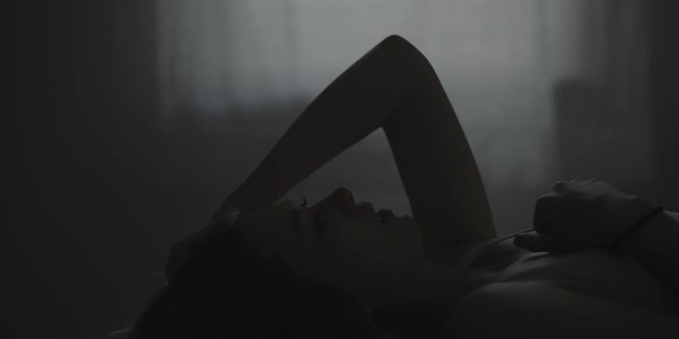 A woman lays in bed with her hand on her head