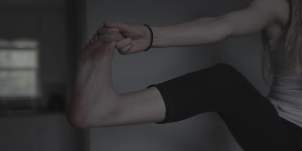 A woman does yoga with an outstretched leg