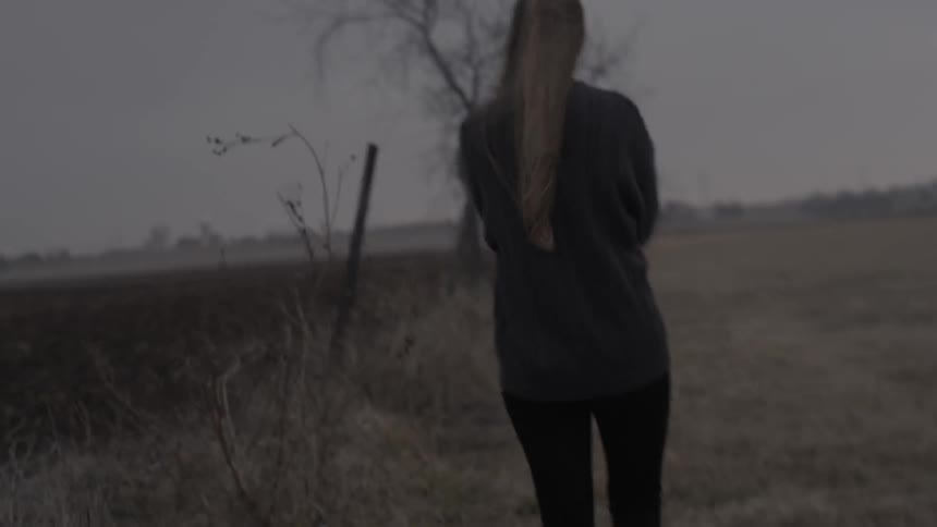 A woman walks in a rural area on an overcast day