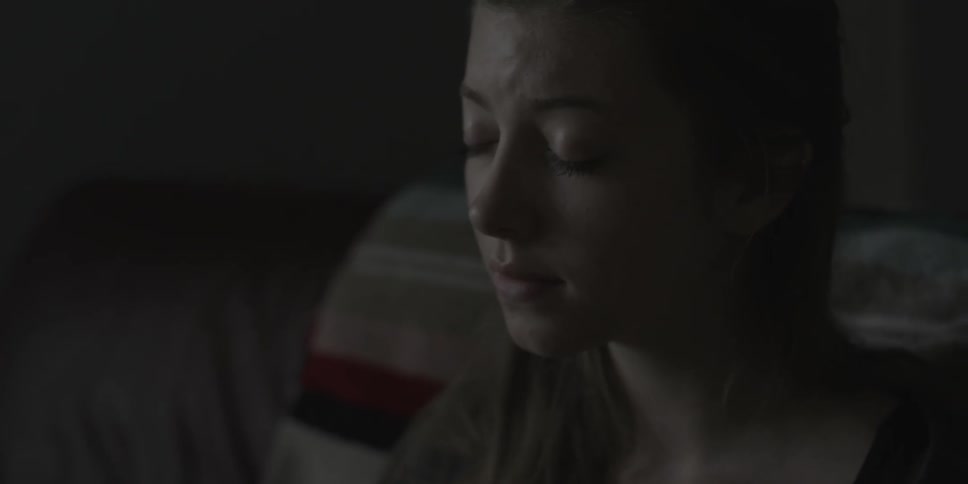 Woman sitting still in a dark room closes her eyes