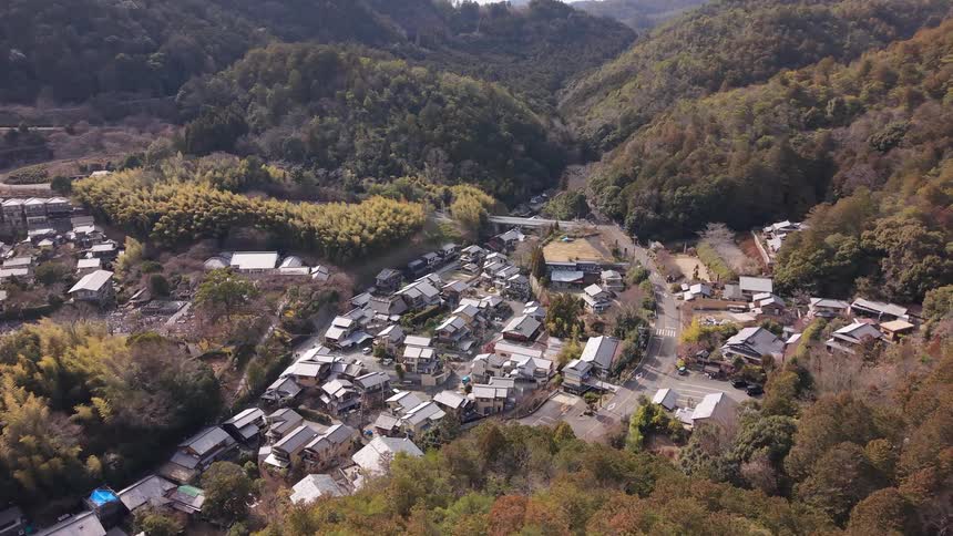 Aerial view moving slowly towards a serene Japanese village nestled in a forested mountain valley