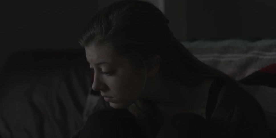 A woman leans forward in a room looking worried