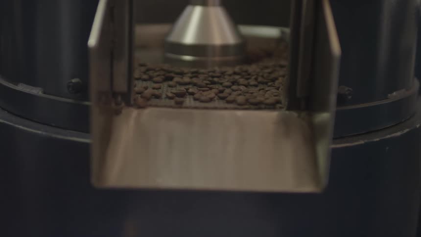 Beans are pushed out through a chute in a coffee roaster