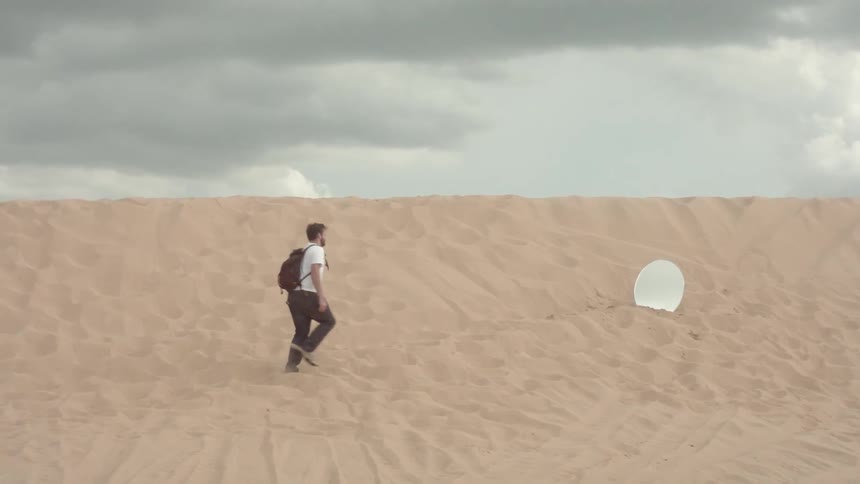 A man walks towards a mirror in the desert
