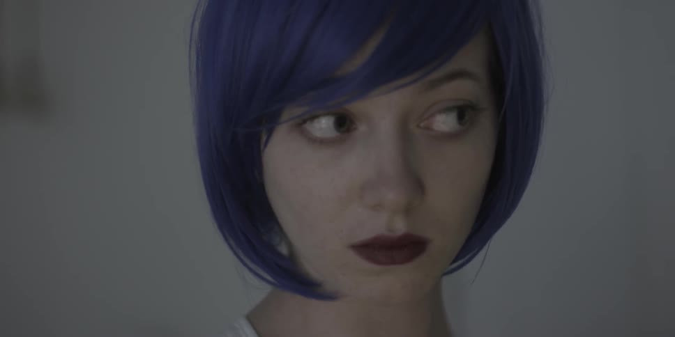 A woman with bright purple hair is going through facial expressions
