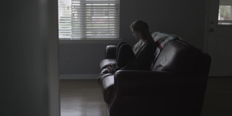 A woman sits on the couch looking out the window