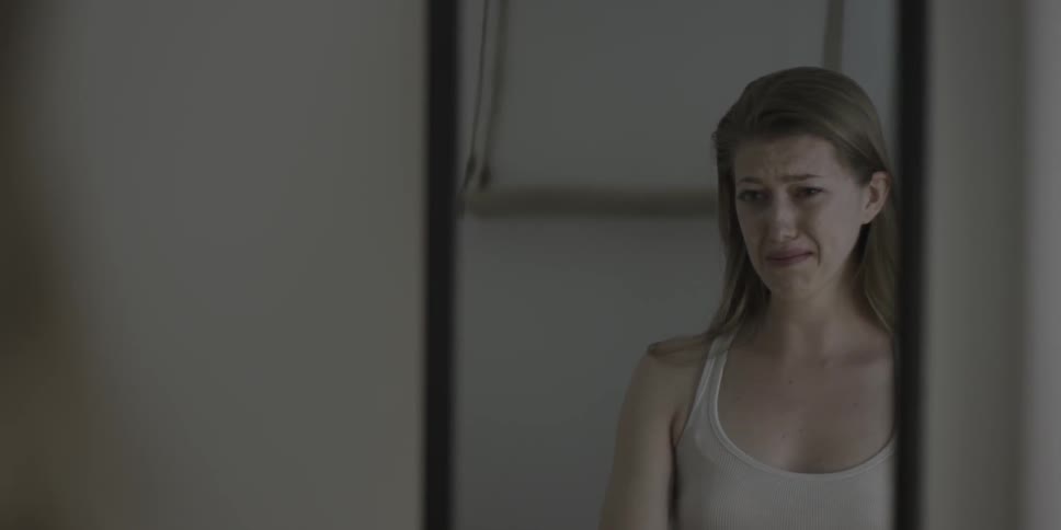 Woman looking at herself in mirror starts to cry
