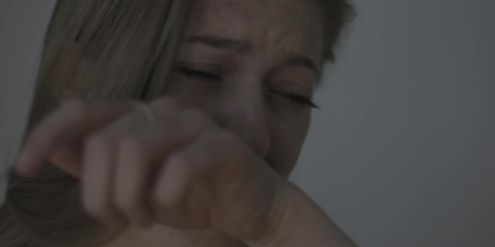 A woman wipes her mouth while crying