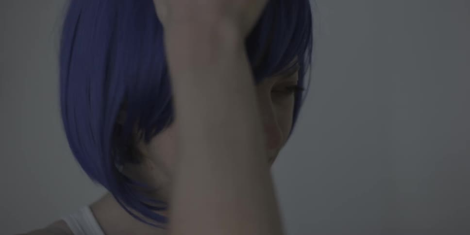Woman wearing short purple wig starts to cry and quickly takes wig off