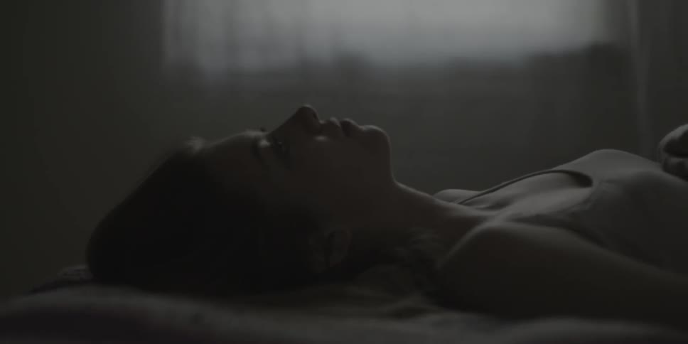 Woman lays on bed looking up at ceiling