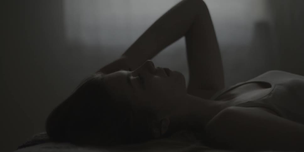 Woman laying on bed plays with her hair