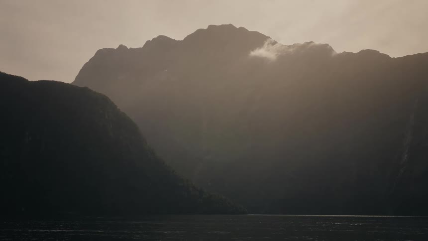 Soft light illuminates the haze over a majestic mountain fjord