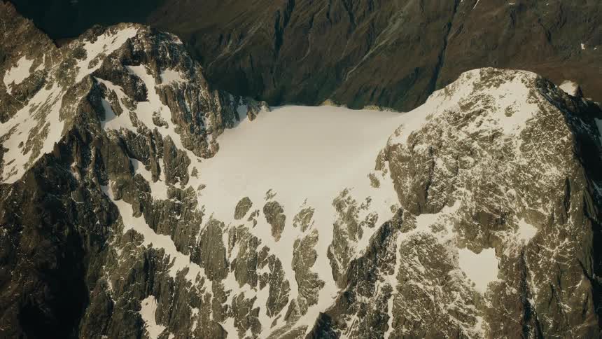 Aerial view of a vast glacier nestled between rugged, snow-dusted mountain peaks
