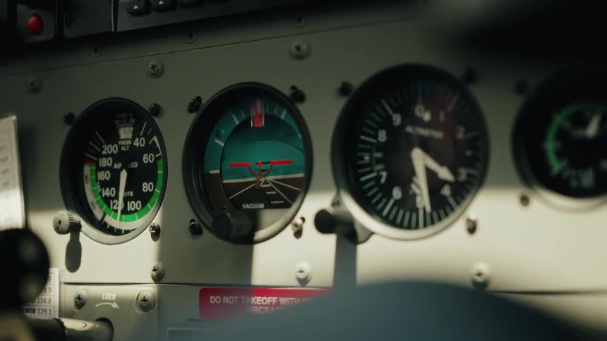 A static close-up shot reveals the analog gauges and dials on the instrument panel inside a small airplane's cockpit