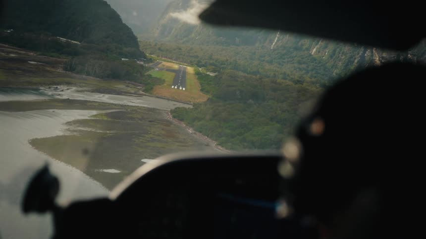 A thrilling over-the-shoulder cockpit view of a small plane landing on a remote airstrip in a breathtaking mountain fiord