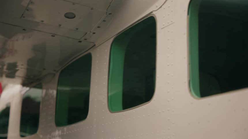 A slow reveal of the green tinted windows along the fuselage of a small white airplane